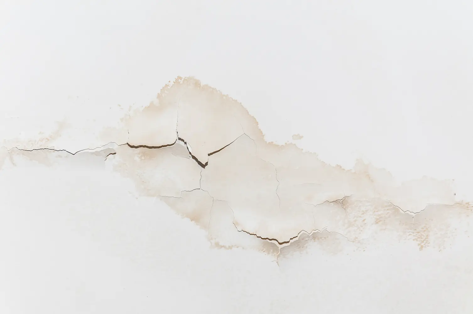 Big wet spots and cracks on the ceiling from water damage after heavy rain